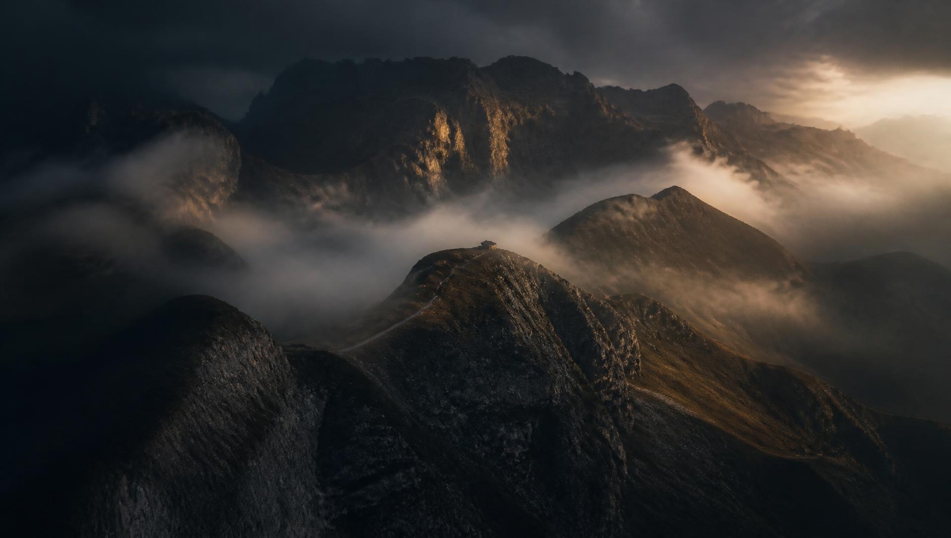 Aerial view of mist rolling over mountain ridges at first light